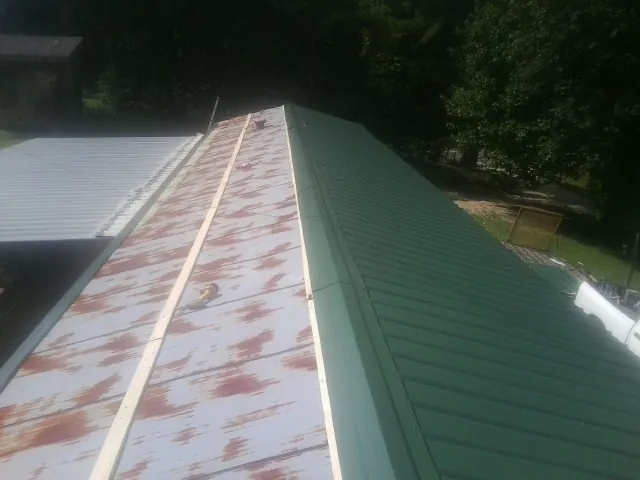 Old rusted panels beside newly installed green metal roofing — Wind Damage Roof Repair by Roofing Brothers in Franklin Park