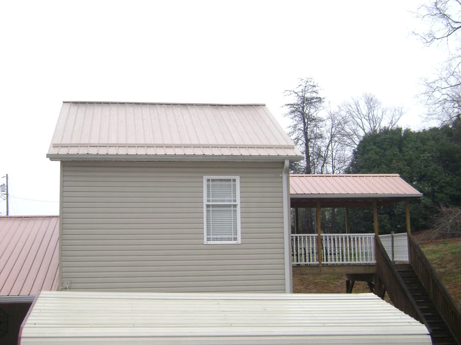 Tan metal roofs on a two story addition and attached porch, from a Roof Replacement job in Franklin Park