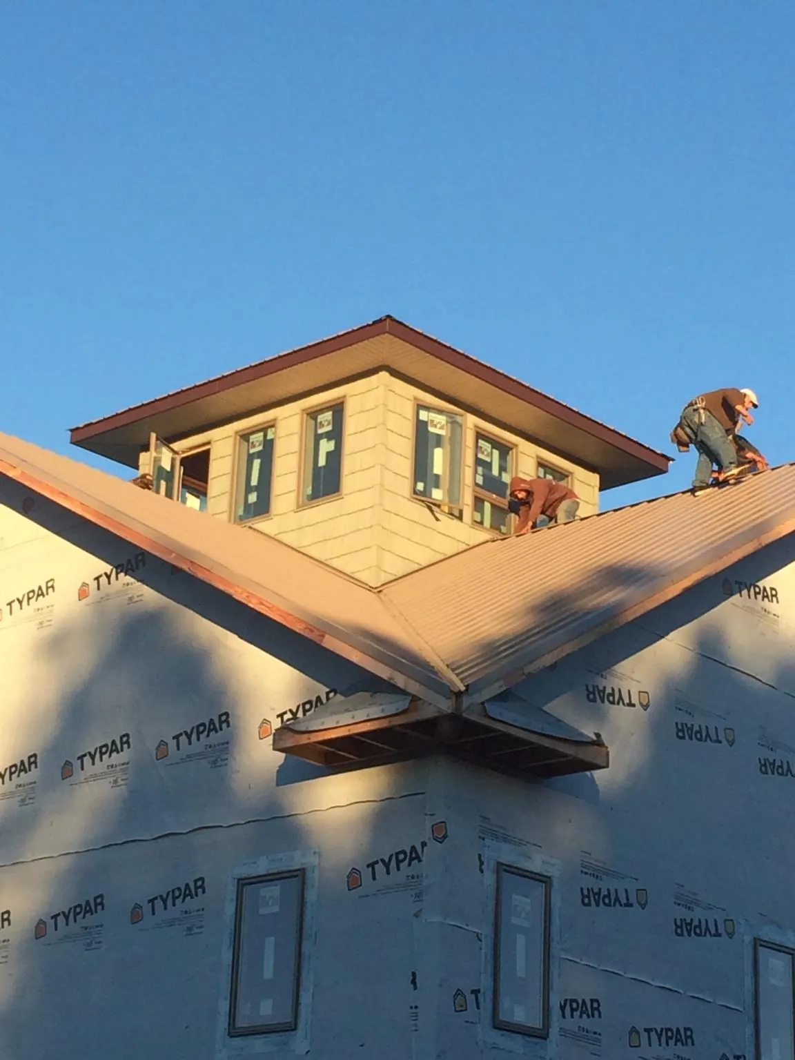 Roofers working around a rooftop cupola on a new metal roof at sunset — Roof Waterproofing in Franklin Park by Roofing Brothers